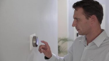 Adam evdeki akıllı termostat aletini ayarlıyor. AC sistemi