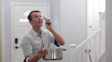 Adam evdeki su sızıntısından sonra acil durum tesisatçısını arıyor. Kızgın Adam 'ın tavandan su sızarken saksıyı tutması Ev' in Yenileme Yavaş Hareketi Gerekiyor 