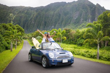 Araba yolculuğu tatilinde gençler yaz tatili sırasında telefonlarıyla selfie çekiyorlar. Turistler, Hawaii 'de üstü açık arabalarla fotoğraf çekiyorlar, akıllı telefon kameralarıyla.