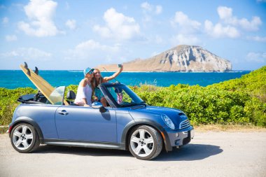 Araba yolculuğu tatilinde gençler yaz tatili sırasında telefonlarıyla selfie çekiyorlar. Turistler, Hawaii 'de üstü açık arabalarla fotoğraf çekiyorlar, akıllı telefon kameralarıyla.
