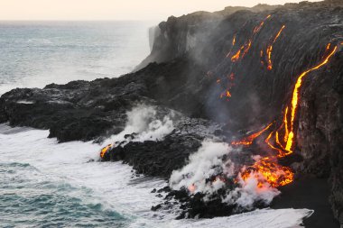 Okyanus dalgaları kayalara ve akan lavlara sıçrarken, Hawaii 'nin Büyük Adası' ndaki Pasifik Okyanusu 'na akan erimiş lav.