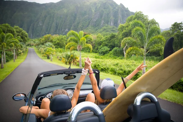 Road trip travel - girls driving car in freedom. Happy young girls cheering in convertible car on summer Hawaii vacations.