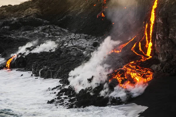 Okyanus dalgaları kayalara ve akan lavlara sıçrarken, Hawaii 'nin Büyük Adası' ndaki Pasifik Okyanusu 'na akan erimiş lav.