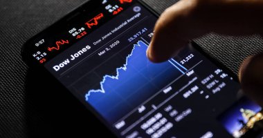 NEW YORK CITY, NY - 23 Mart 2020: Evdeki gece odasında akıllı telefonlu bir erkek borsayı kontrol ediyor.