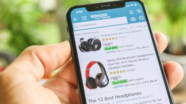 NEW YORK CITY, NY - 1 Aralık 2019: Mobil Akıllı iPhone ile Amazon uygulamasında kulaklık arayan adam
