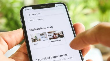 NEW YORK CITY, NY - 1 Aralık 2019: Airbnb uygulamasını kullanarak New York 'ta ev kiralamaya çalışan kadın