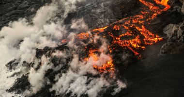 Okyanus dalgaları kayalara ve akan lavlara sıçrarken, Hawaii 'nin Büyük Adası' ndaki Pasifik Okyanusu 'na akan erimiş lav.
