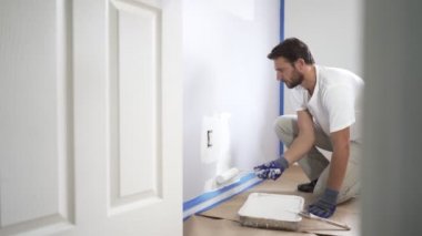 4K, boyacı evin duvarını boyuyor, boya rulosu ve beyaz boyayla. Evdeki oda tadilatı.
