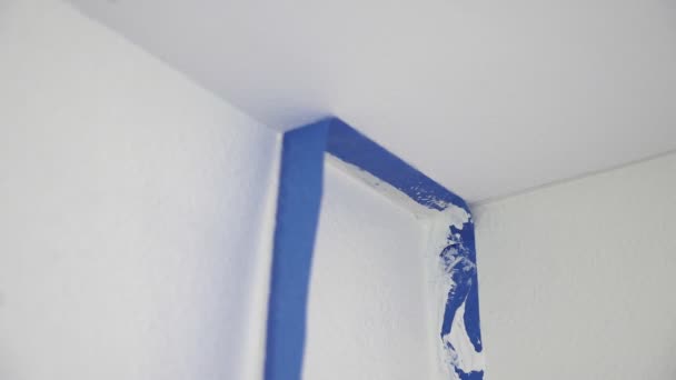 从天花板上取下掩蔽带 油漆工从墙上抽出蓝色油漆纸带的油漆工 用天花板露出干净的边缘 — 图库视频影像
