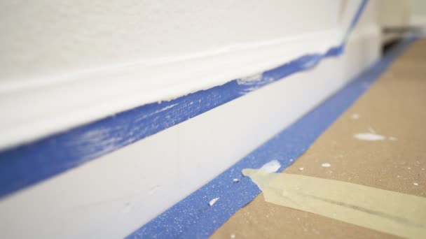成形からマスキングテープを外します 壁から青い画家のテープを引っ張り きれいなエッジのベースボードを明らかにします — ストック動画
