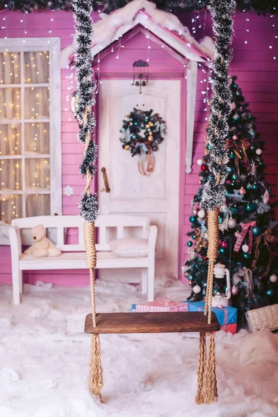 Kinder-Holzschaukel am Seil in der Silvesternacht mit Weihnachtsbaum und Spielzeug in sanften Tönen — Stockfoto