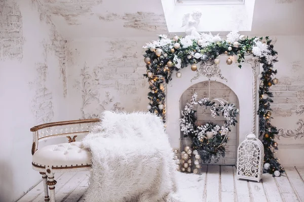 Canapé exclusif blanc avec dorure sur le fond de la cheminée. Décorations de Noël de branches et jouets d'arbres de Noël . — Photo