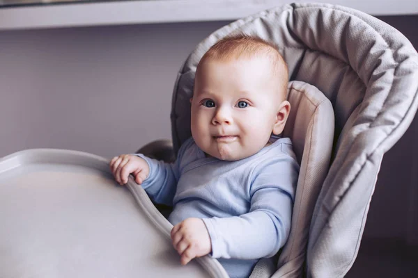 A small child is sitting in a soft baby seat and smiling — Stock Photo, Image