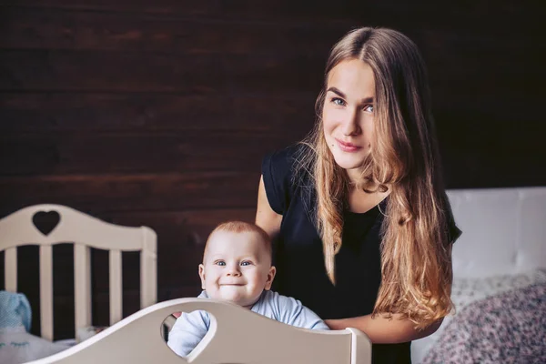 Mama i dziecko są pozowanie. Dziecko wychodzi łóżeczko — Zdjęcie stockowe