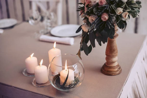 Table de mariage avec un bouquet de fleurs dans un vase et des bougies allumées — Photo
