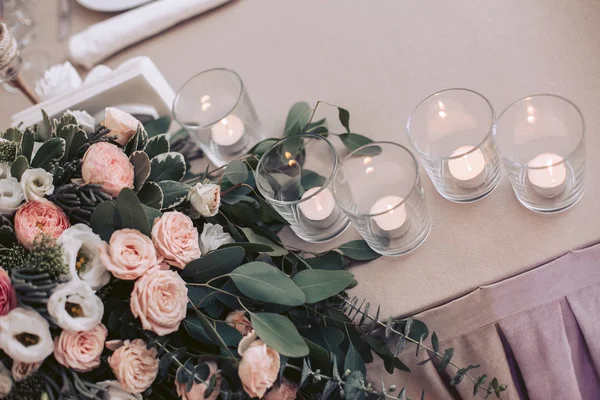 Une table au mariage ornée d'un bouquet de roses et de bougies dans des verres — Photo