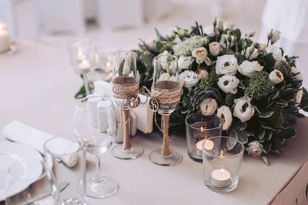 Un bouquet de fleurs avec des verres et des bougies sur la table de mariage — Photo