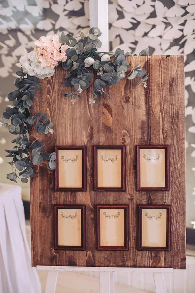 Деревянная доска с рамами в багете, украшенная цветами, установленными на мольберте — стоковое фото