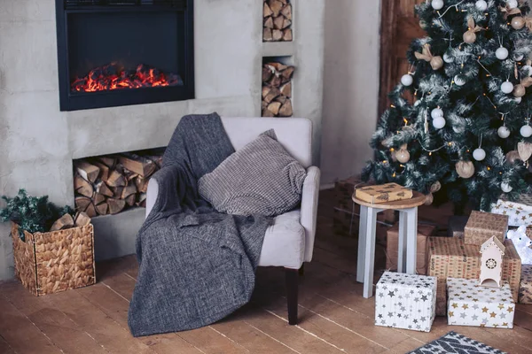 Hoş bir koltuk yeni yıl bir şömine, yakacak odun ve bir Noel ağacı ile iç — Stok fotoğraf