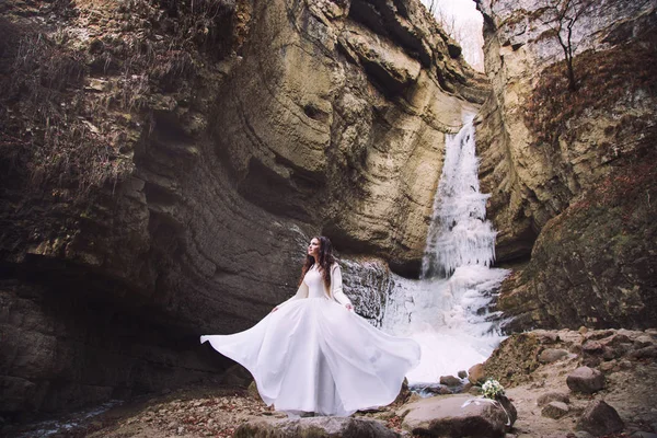 Невеста в шикарном свадебном платье стоит на фоне ледника — стоковое фото