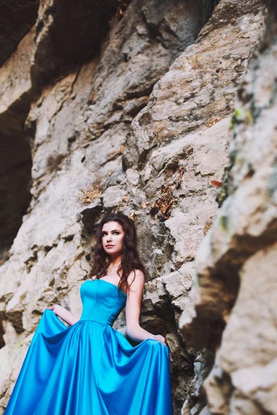 Uma menina doce está de pé ao lado de uma montanha em um vestido azul — Fotografia de Stock