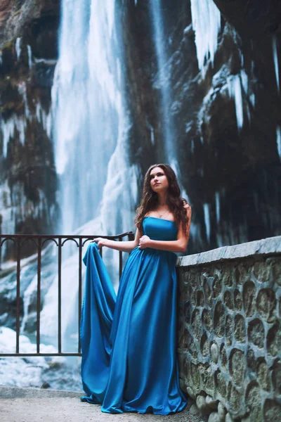 Bir buzul ve dağlar arka plan üzerinde duran mavi elbiseli güzel genç kız — Stok fotoğraf
