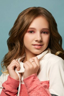 Stüdyodaki fotoğraf çekimi sırasında kalın kazaklı ve parlak makyajlı esmer bir kız. Mutlu genç kız.