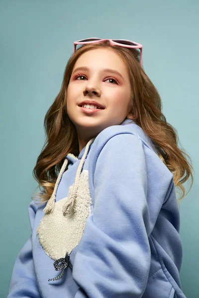 Bonita jovem morena com um sorriso encantador posa em um fundo azul em um estúdio de fotos . — Fotografia de Stock
