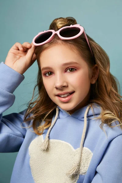 Menina bonita nova com penteado posando em estúdio no fundo. Morena em óculos rosa elegantes e um suéter lilás . — Fotografia de Stock