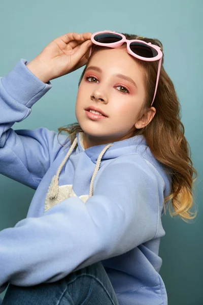 Молодая девушка в стильных розовых очках позирует в студии. Брюнетка в повседневной одежде . — стоковое фото