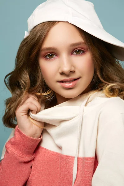 Menina bonito com um sorriso encantador posando em roupas casuais em um fundo azul. Adolescente maquiagem brilhante — Fotografia de Stock