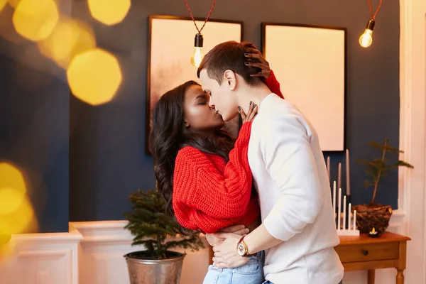 Interracial pareja casada besándose en San Valentín día de fiesta. Un tipo abraza a una chica negra en la cintura. Relación feliz . Fotos De Stock Sin Royalties Gratis