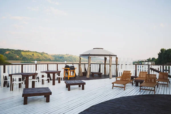 Place of rest on the landing stage. Cafe by the water with wooden tables and chairs. Outdoor recreation. — 스톡 사진