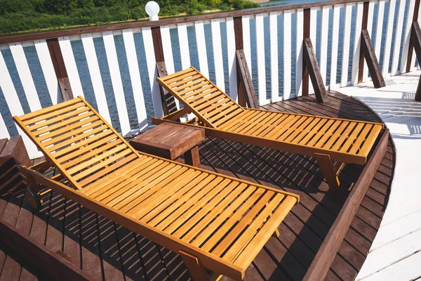 Stylish wooden sunbeds on the terrace of the landing stage. Outdoor recreation. River on the background. — 스톡 사진