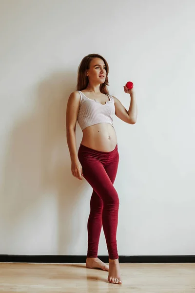 Een bruinharig meisje is bezig met fitness voor de bevalling. Sport levensstijl. Til de halter op met je hand.. — Stockfoto