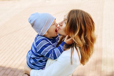 Güzel, genç bir anne, şehrin sokaklarında yürürken kucağında küçük bir çocuk tutuyor. Güzel, güneşli yaz havası.