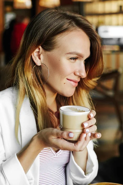 街を歩いていると カフェで贅沢な女の子がコーヒーを飲みます 美人さんホットドリンクのマグカップを持っています — ストック写真