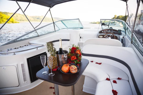 沿着河边的一条豪华的白色游艇上散步 有水果 花和清凉香槟的桌子 图库图片