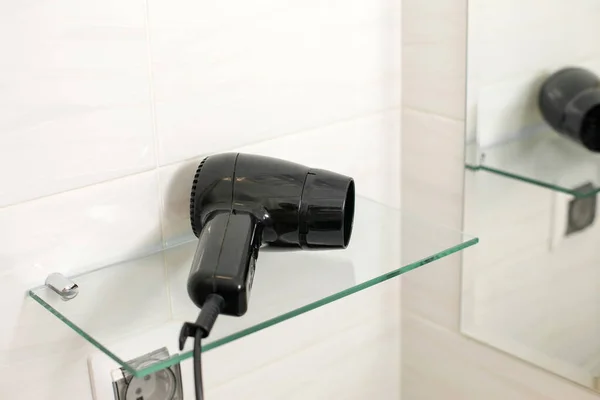 Κοντινό Μαύρο Στεγνωτήρα Μαλλιών Ένα Γυάλινο Ράφι Στο Μπάνιο Εικόνα Αρχείου