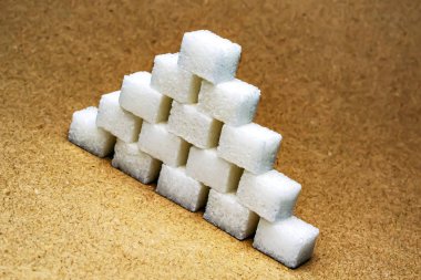  sugar cubes stacked in a pyramid with a slope on a beige background