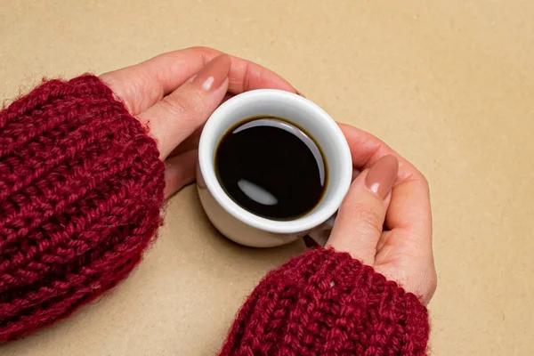 穿着毛衣的手抱着一杯米色背景的咖啡 — 图库照片