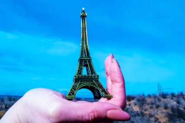  Sert el, Eyfel Kulesi 'nin bir heykelini gökyüzüne karşı tutuyor.