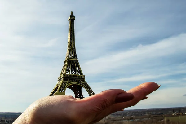 Figurine Eiffel Tower on a hand against the sky