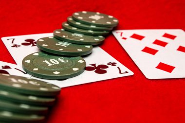 Kırmızı bir grupta iki kart ve poker fişi.