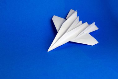 Beyaz kağıt uçak mavi arka planda uçuyor.