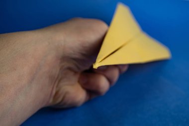 Elinde kağıt sarısı bir uçak var. Bulanık arkaplan