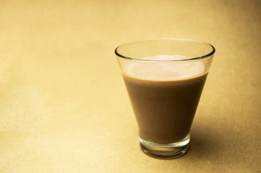 Bej arka planda, cam bardakta kakao sütü.