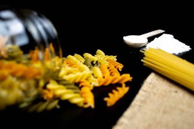 Makarna, spagetti, un, siyah arka planda tahta kaşık.