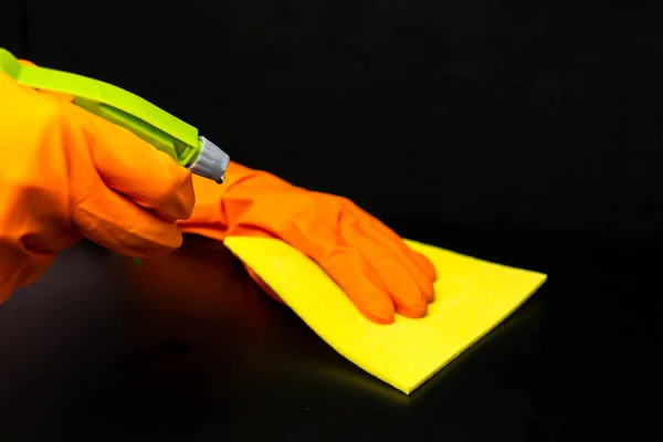Hands in rubber gloves wipe dust with a rag
