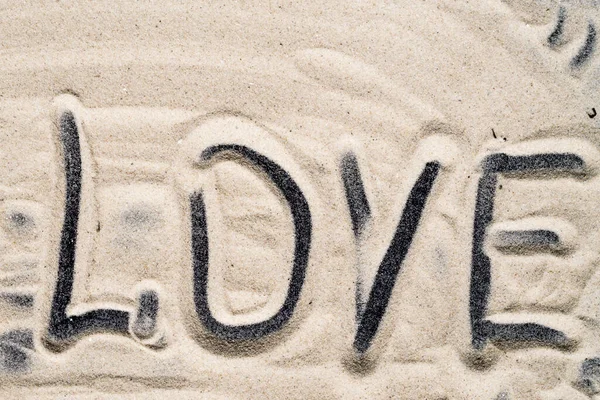 Inscription love on sea sand close up